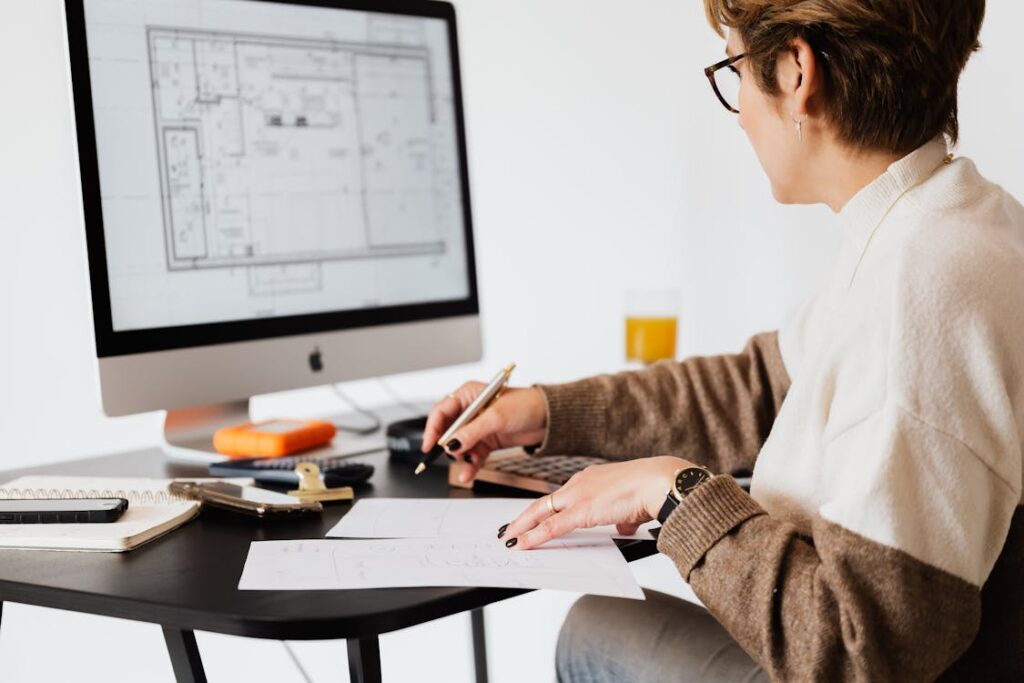 Woman reviewing home floor plans with calculator, representing mortgage refinancing decisions